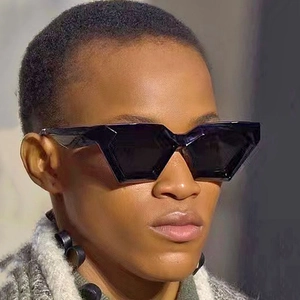 Close-up of black geometric cat-eye sunglasses with bold hexagonal frames on a model