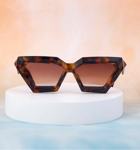 Detailed view of tortoiseshell geometric sunglasses on a platform with clear hinge details