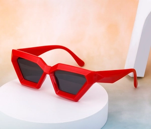 Detail of red geometric cat eye sunglasses displayed on white minimalist platform