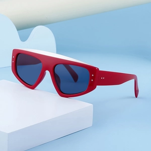 Détail de lunettes de soleil œil-de-chat rouges avec rivets sur support bleu et blanc