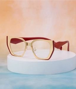 Detail of trendy cat-eye sunglasses featuring a red base and champagne gold metal frame