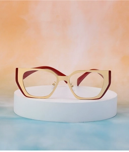 Detail of geometric cat-eye sunglasses with gold metal frames and red temples on base