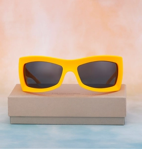 Detail einer neongelben quadratischen Sonnenbrille auf umweltfreundlicher Verpackung