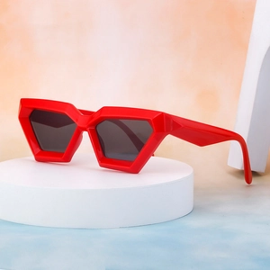 Fashionable red hexagonal geometric sunglasses with dark lenses on a white display stand