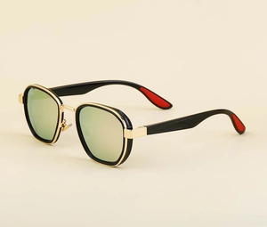 Detail view of oval sunglasses with gold metal frame and red temple accents