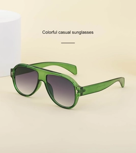 Detail of pilot sunglasses with green frames and purple gradient lenses in studio setting