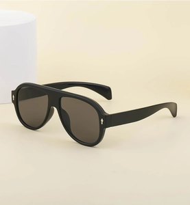 Detail view of matte black pilot sunglasses with textured temple tips on a minimalist base