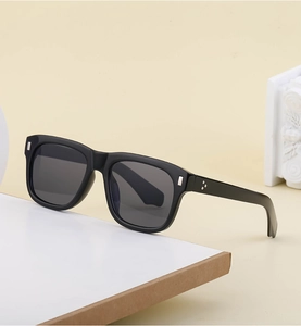 Close-up of black square sunglasses featuring silver metal accents and 3-dot rivets