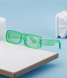 Detail of trendy green translucent rectangular sunglasses on a minimalist white pedestal