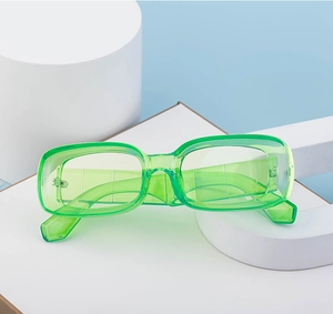 Detail view of stylish translucent neon green square frame sunglasses on a geometric stand