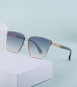Detail of rose gold sunglasses with chain temples and gradient blue lenses