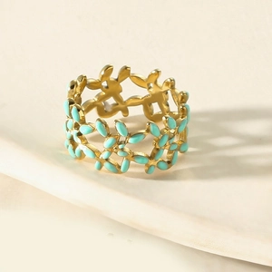 Macro view of floral enamel ring with gold branches and mint green petals on stone