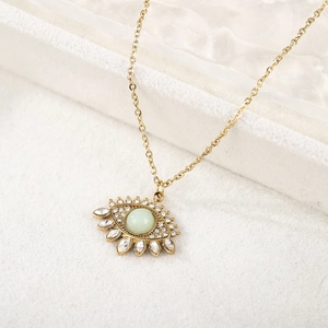 Détail macro du pendentif œil doré avec pierre verte et pierres de zircone brillantes