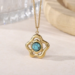 Macro view of gold hollow flower pendant with turquoise bead on a fine crossbody chain