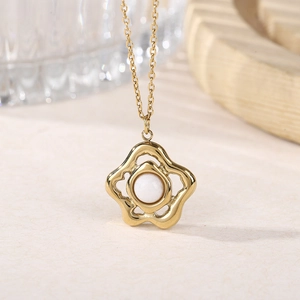 Detail of gold hollow flower necklace with white pearl center on elegant display