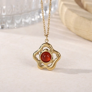 Elegant gold flower pendant necklace featuring a round red gemstone in a vintage style