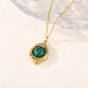 Détail d'un collier en titane doré avec pendentif goutte et pierre de malachite verte
