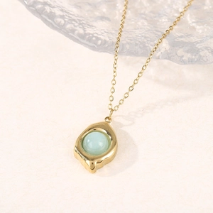 Détail du collier doré avec pendentif goutte d'eau et incrustation de pierre bleue
