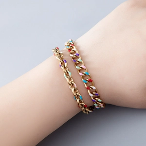 Close-up of gold chain bracelets with colorful enamel drops and polished finish