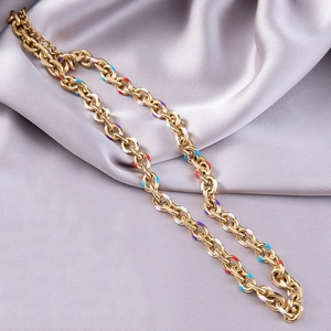 Close-up of golden link chain necklace with colorful enamel dots on silk background