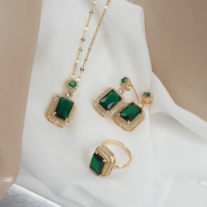 Detailed set of gold titanium steel jewelry with emerald green stones and zircon accents