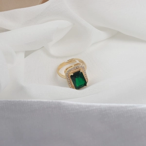 Gold plated open ring with emerald green square stone and zircon halo on white fabric