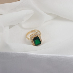 Macro view of adjustable gold ring with emerald cut green stone and zircon halo