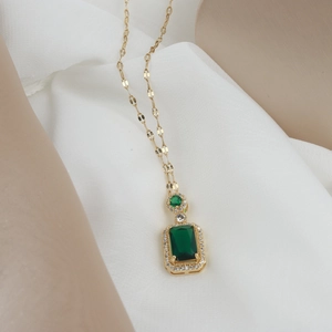 Detailed close-up of emerald green rectangle pendant with zircon halo on gold chain