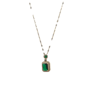 Emerald cut green zircon necklace with gold chain and diamond accents on white background