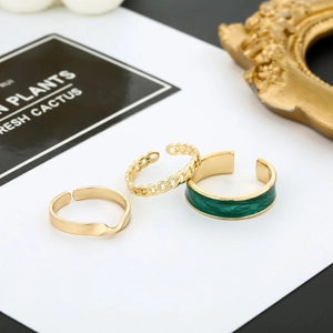 Dettaglio del set di 3 anelli dorati regolabili con smalto verde e design a catena