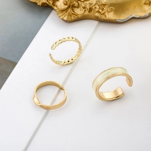 Set di tre anelli dorati regolabili con un anello largo in smalto crema e catena