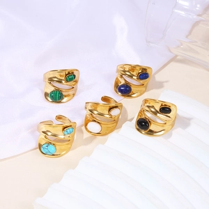 Macro detail of wide gold rings featuring inlaid oval malachite and turquoise gemstones