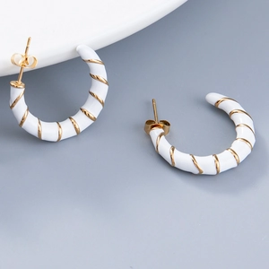 Boucles d'oreilles créoles C émaillées blanches avec détails spirales dorés sur fond gris