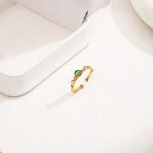 Detail of bamboo-style gold open ring featuring a green cabochon and zircon accents