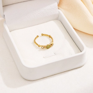 Macro detail of gold bamboo-textured ring with oval green stone and zircon accents