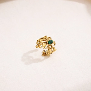 Detailed shot of a gold flower ring with green stone and adjustable open band