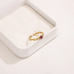 Detailed macro view of a gold flower hollow ring with a round purple gemstone and zircon