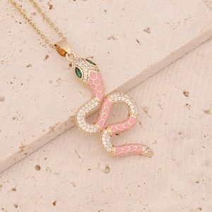 Détail macro du pendentif serpent avec émail rose, cristaux pavés et yeux verts sertis