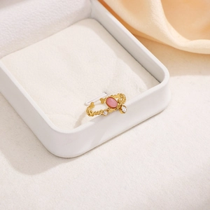 Detail of gold-plated wavy ring with oval pink stone and side zircon in a jewelry box