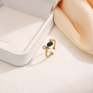 Macro detail of gold beaded adjustable ring with oval green stone and white rhinestones