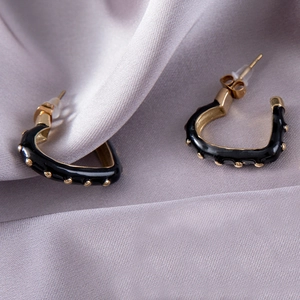 Élégantes boucles d'oreilles cœur dorées avec émail noir sur fond de satin doux