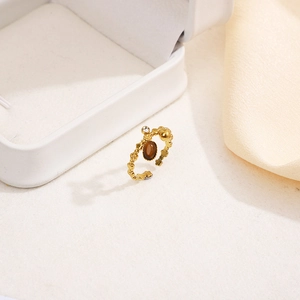 Détail d'une bague en acier doré avec pierre naturelle marron et oxyde de zirconium