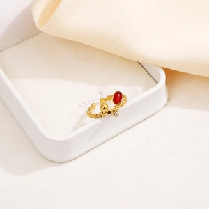 Détail d'une bague dorée vintage avec pierre rouge et cristal sur tissu en soie