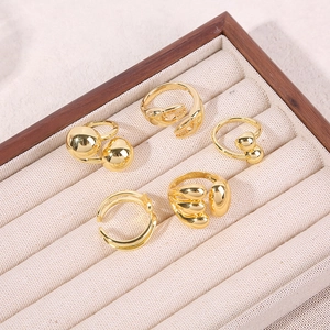 Set of five gold geometric ocean-inspired rings displayed in a luxury wooden tray