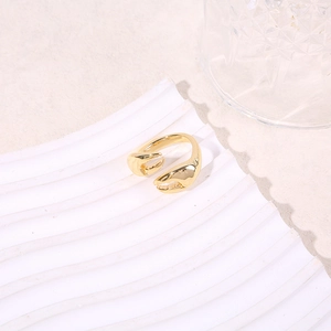 Macro shot of gold-plated crab claw open ring on a minimalist white textured base