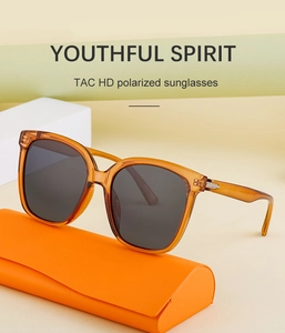 Detail view of amber polarized sunglasses on orange leather case with TAC HD lens feature