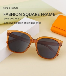 Close-up of amber square polarized sunglasses displayed on white geometric props