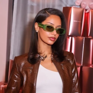 Gros plan de lunettes de soleil rectangulaires étroites vert foncé portées par un mannequin