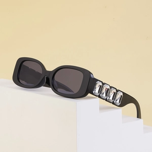 Détail de lunettes de soleil noires rectangulaires avec cinq grands cristaux verticaux sur la branche