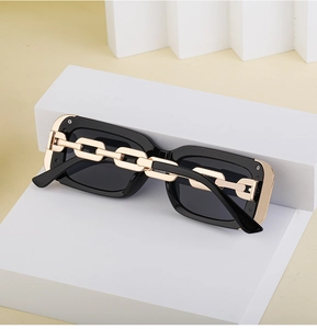 Detail of square sunglasses with thick gold chain link decoration on black frame